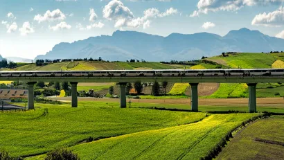 AI-generated image of high-speed rail trail in elevated track in green hilly farmland.