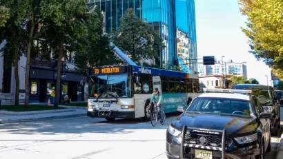 Public transit bus on street with cyclist riding next to it in Madison, Wisconsin.