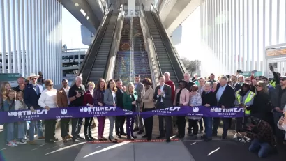 Group of officials cutting purple ribbon.