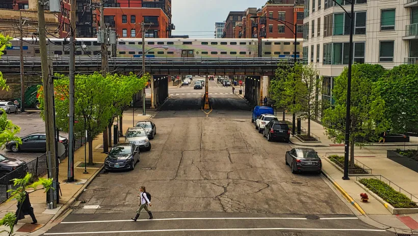 Chicago elevated train passing over street with parked cars.