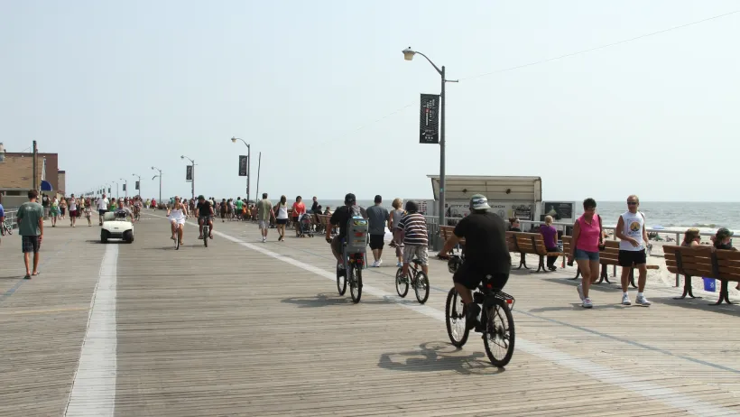 People riding bikes and walking on boardwalk in Long Beach, New York.