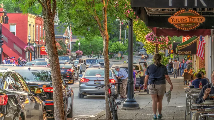 Person walking down wide sidewalk next to restaurant patio tables in Chagrin Falls, Ohio.