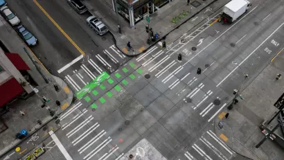An almost empty intersection in downtown Seattle Washington. An arial shot off of the side of a building that shows the crisscrossing of roads, crosswalks, and bike lanes.