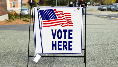 "Vote Here" sidewalk sign with American flag