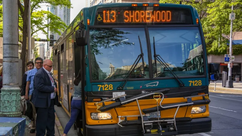 People board an orange bus in Seattle.