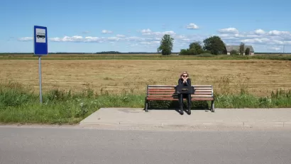 Woman sitting on bench at rural bus stop