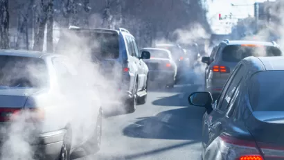 View of cars in traffic from behind with visible tailpipe emissions