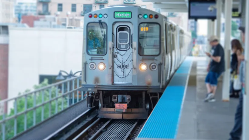 Silver CTA train pulling into elevated platform station in Chicago, Illinois.