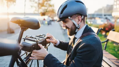 Young bearded man with helmet setting up battery on back of electric bike
