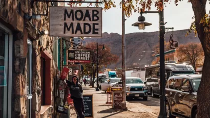 Person standing under sign that says "Moab Made" in downtown Moab, Utah.