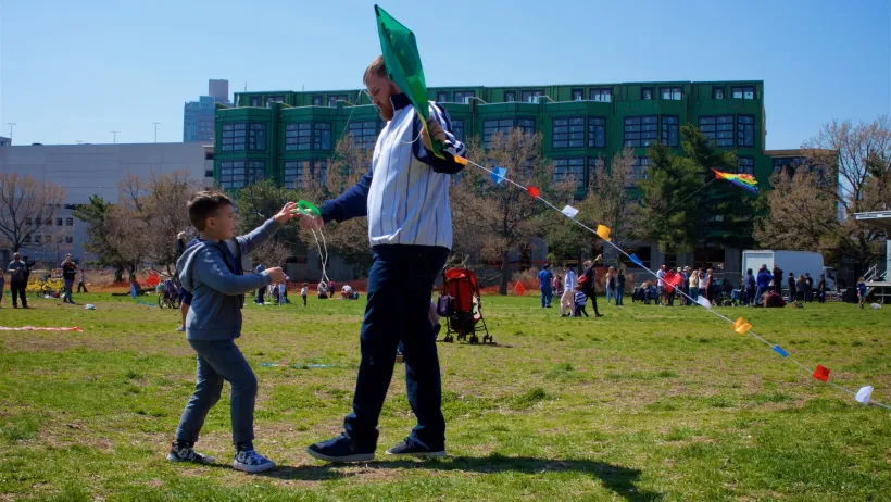 Child and adult man playing with kite in park in Philadelphia, Pennsylvania on a sunny day.