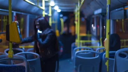 Nighttime bus interior with one rider standing by door