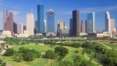Aerial view of green Memorial Park lawns and trees with downtown Houston skyline in background