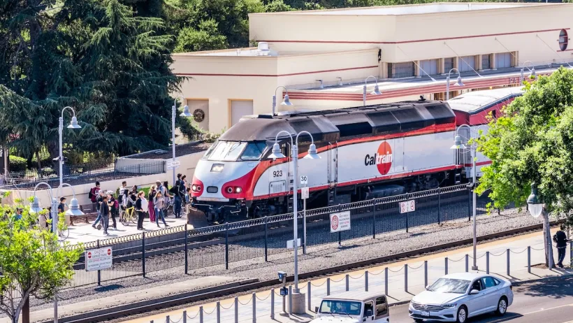 A Caltrain train picks up a large crowd of people at a station.