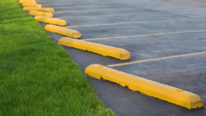 Parking lot with yellow concrete bars adjacent to green grass