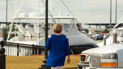 Woman walking at marina in Pensacola, FL with boat in background