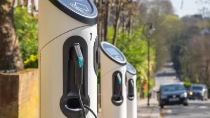 Row of curbside electric vehicle chargers with black car approaching in background