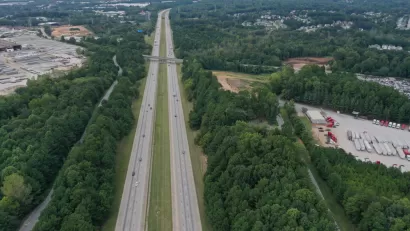 Aerial view of freeway cutting through green forest in Clayton County, Georgia