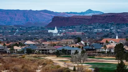 Town of St. George, Utah with small white church and red rock cliffs in background