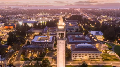 Aerial view at dusk of UC Berkeley campus with tall tower in foreground and San Francisco Bay in the background