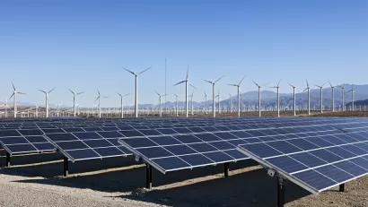 Solar array and wind turbines in California with mountains in background