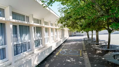 Schoolyard with leafy green trees surrounded by benches 