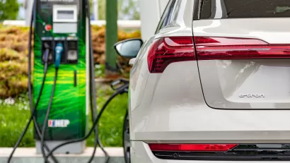 Close-up of back of white electric Audi SUV plugged into charging station