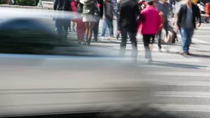 People in crosswalk with blurred fast car passing in foreground