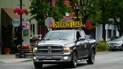 Pick-up truck on small town street with yellow "Oversize Load" sign