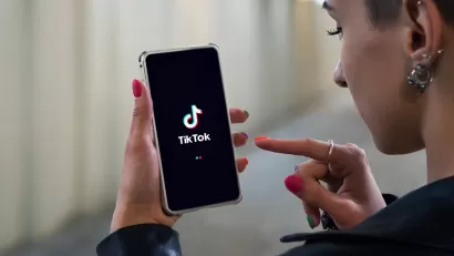 Woman holding phone with TikTok logo