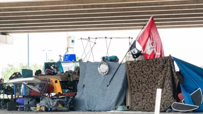 Encampment of unhoused people with tents and draped fabrics in Austin, Texas