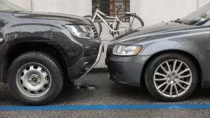 Two grey cars parked head to head at a curb with a white bike in background