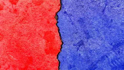 Concrete wall with crack running down the middle painted red on one side and blue on the other