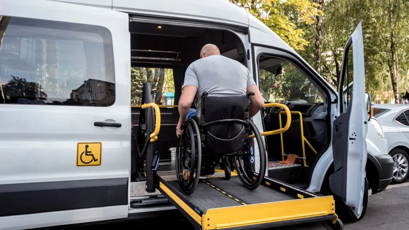 Man in wheelchair entering paratransit van on ramp.