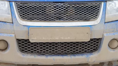 Close-up of license plate on blue car covered in mud, license plate is unreadable.