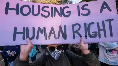 Protester at Echo Park Lake, Los Angeles holding sign that says "Housing is a human right"