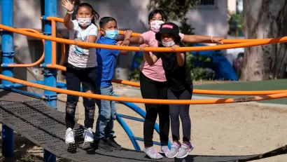 Children wearing COVID-19 masks on playground equipment