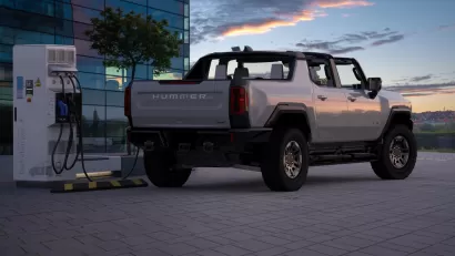 Rendering of grey convertible electric Hummer charging at a charging station against a sunset sky