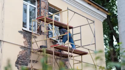 Man on a scaffold repairs a stucco wall.