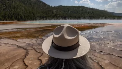 View of park ranger with tan hat from behind, ranger looking out at Grand Prismatic Spring in Yellowstone National Park, Wyoming