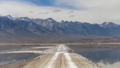 Unpaved road through Owens Lake bed with Sierra Nevada mountains in the background
