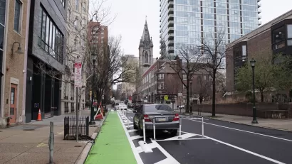 Green parking-protected bike lane in Philadelphia with old church in background