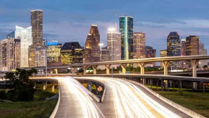 Dusk view of blurred car lights passing on freeway with Houston skyline in background