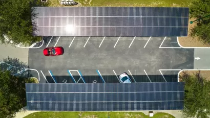 Overhead view of parking lot with solar panel canopies over parking spots and red car driving in