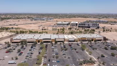 Aerial view of sprawling commercial development with parts still under construction and parking lot in Goodyear, Arizona