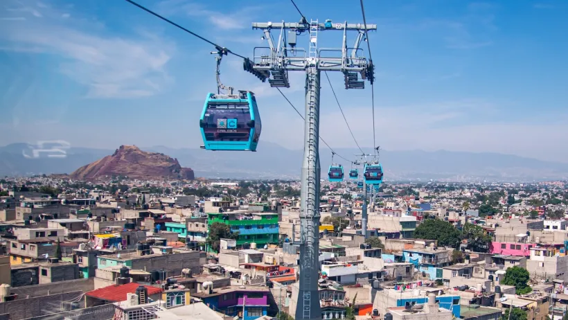 Blue aerial gondolas over colorful Mexico City neighborhood.