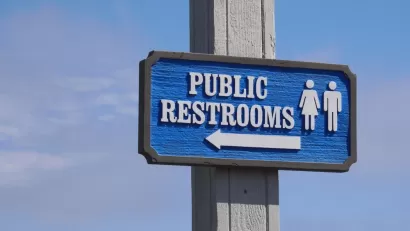 Blue "Public Restrooms" sign with arrow against a blue sky