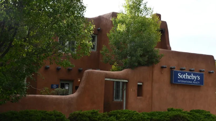 Adobe-style building in downtown Santa Fe, New Mexico with Sotheby's realty sign.