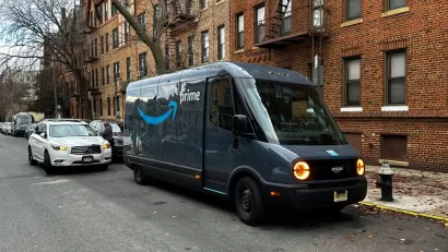 Rivian electric Amazon delivery van delivering packages curbside on New York City street