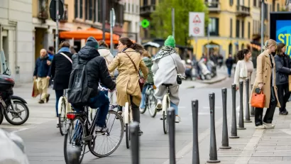 People on bikes and pedestrians walking on busy city street in Milan, Italy